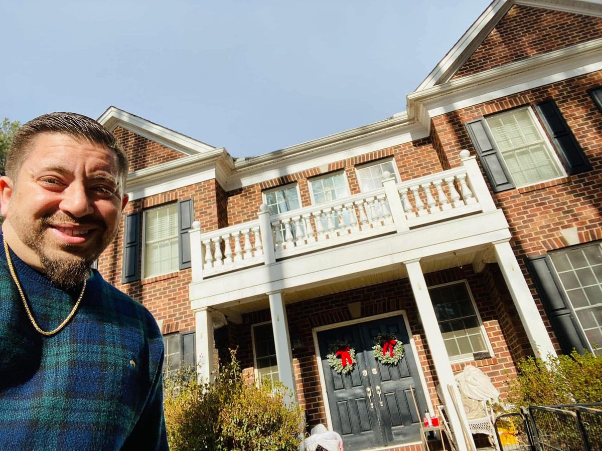 A Real Hope team member smiling in front of a brick colonial home